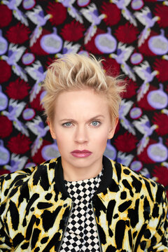 Flashy glamour photography. Portrait of young fashionable woman with short spiky hairstyle grimacing at camera on patterned background