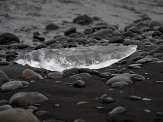 block of ice on black and volcanic sand