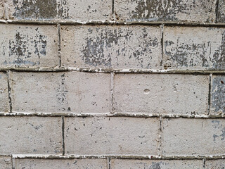 Close up of old concrete block wall with peeling paint and rough texture