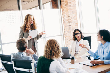 Business professionals collaborating in a modern office space during a team meeting with discussions and brainstorming.