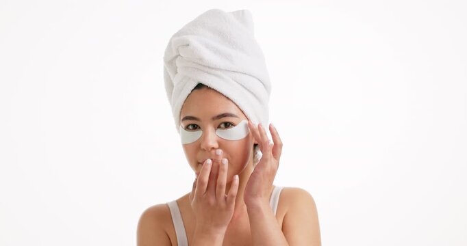 Woman, face and eyes patches with towel in studio for skincare or collagen on a white background. Portrait, female person or model with smile, mask or beauty cosmetics for anti aging on mockup space