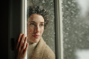 person gazing at animated falling snow through window immersed in augmented reality