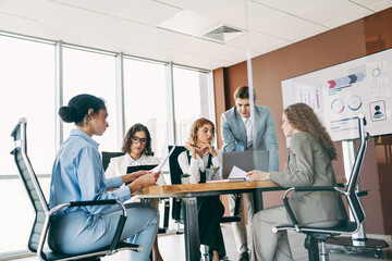 Professional team collaborating in a modern office workspace while planning a project on a laptop with diverse perspectives