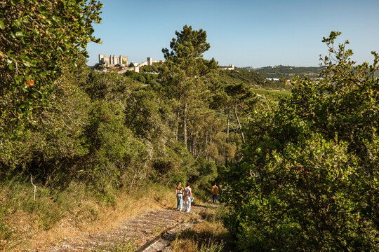 The family climbing the stairs on the tourist trail  to the Portuguese Christian religious temple Ermida de Santo Ant&atilde;o, with views of &Oacute;bidos Castle in the background,  Portugal.