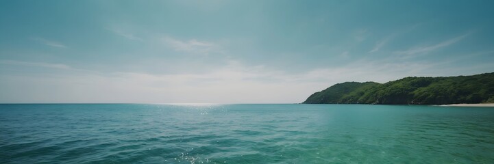 Obraz premium Calm Ocean View with Green Hills Under Bright Blue Sky