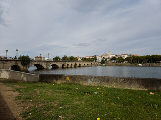 The historic granite Old Bridge crosses the Tua River in Mirandela, Portugal with the cityscape and iconic tower behind. This scenic pedestrian landmark blends heritage and beauty in northern Portugal