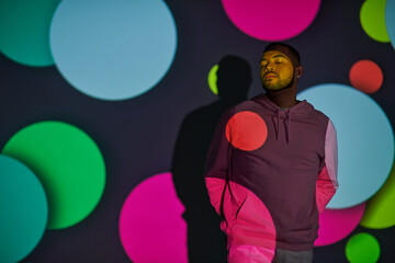 Young man showcases trendy fashion in vibrant colorful backdrop at modern venue