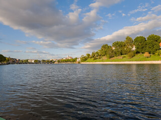 Wide view of the Tua River in Mirandela, Portugal, with the pedestrian bridge and city skyline in the distance. Evening clouds and tranquil water highlight this urban landscape and natural beauty.