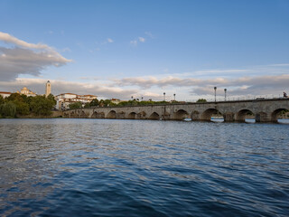 The historic granite Old Bridge crosses the Tua River in Mirandela, Portugal with the cityscape and iconic tower behind. This scenic pedestrian landmark blends heritage and beauty in northern Portugal