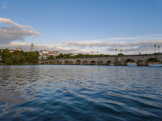 The historic granite Old Bridge crosses the Tua River in Mirandela, Portugal with the cityscape and iconic tower behind. This scenic pedestrian landmark blends heritage and beauty in northern Portugal