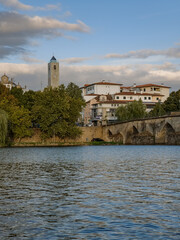 The historic granite Old Bridge crosses the Tua River in Mirandela, Portugal with the cityscape and iconic tower behind. This scenic pedestrian landmark blends heritage and beauty in northern Portugal