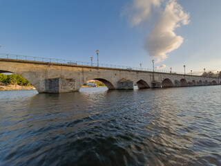Stone bridge over the Tua River in Mirandela, Portugal, with granite arches and pedestrian use. August 2025, peaceful historic landmark connecting old city sides.