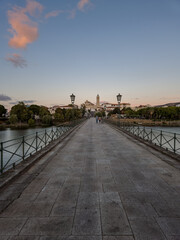The historic granite Old Bridge crosses the Tua River in Mirandela, Portugal with the cityscape and iconic tower behind. This scenic pedestrian landmark blends heritage and beauty in northern Portugal