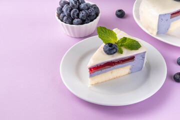Tasty berry layered mousse tart cake with blueberries and white with white chocolate glaze, cut into portioned pieces. Cafe, confectionery menu background