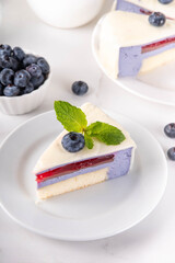 Tasty berry layered mousse tart cake with blueberries and white with white chocolate glaze, cut into portioned pieces. Cafe, confectionery menu background