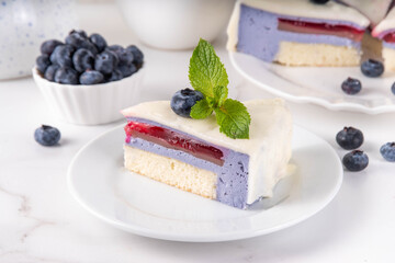 Tasty berry layered mousse tart cake with blueberries and white with white chocolate glaze, cut into portioned pieces. Cafe, confectionery menu background