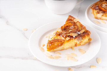 Traditional French almond cake with frangipane and apricots, sweet fruit pie with a fragrant caramelized top, almond petals and powdered sugar on it
