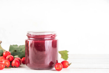 Wild forest hawthorn berry jam or marmalade in small jar with fresh berries on kitchen table, copy space