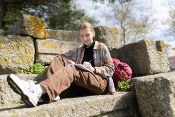 Fototapeta premium Young archaeologist writing notes outdoors on ancient ruins