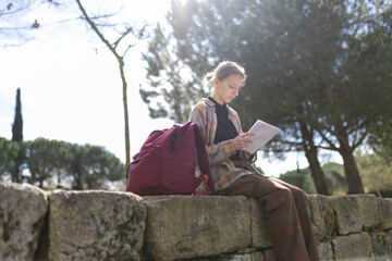 Fototapeta premium Young student studying outdoors in a park reading notes