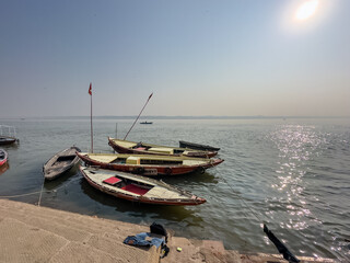 Wooden boats floating or parked at the banks of river ganga in varanasi during winter morning.