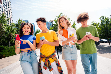 Group of young diverse friends enjoying their time together outdoors while using smartphones