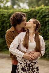 Fototapeta premium Couple shares a loving kiss while strolling through a peaceful park in the afternoon sun
