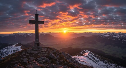 Majestic mountain summit cross at sunrise with dramatic fiery clouds