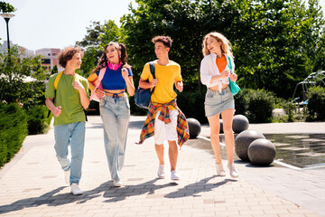 Group of young friends walking outdoors on a sunny day, enjoying leisure time and casual...