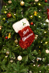 A magical festival Christmas tree decorated in red sock hanging , gold ornaments, glistening baubles, twinkling fairy lights, soft snow , delicate snowflakes, and sparkling shimmering stars.