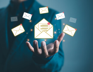 Businessman hand holding digital email icons with new message notifications, symbolizing online communication, email marketing, customer service, and modern business technology.
