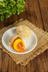 Golden Salted Egg Yolk Pastry Dessert on Rustic Wooden Table with Fresh Greens