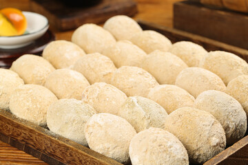 Raw bread dough balls covered in flour in wooden tray ready for baking