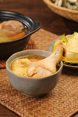 Traditional Asian Chicken Soup with Drumstick in Ceramic Bowl on Bamboo Placemat