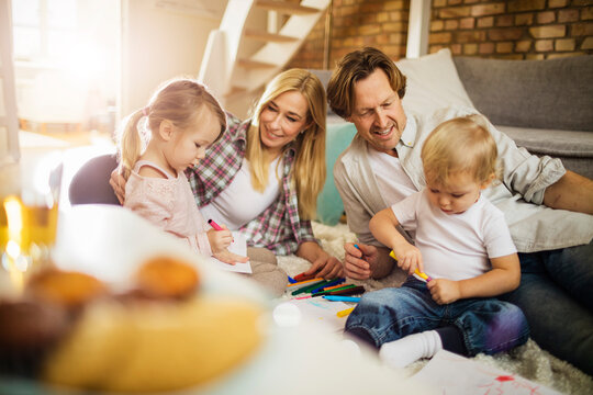 Family playing together while drawing and coloring in the living room at home