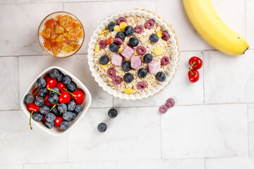 Healthy Oatmeal Breakfast Bowl with Fresh Berries and Fruit on White Marble Background