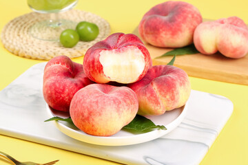 Fresh Flat Peaches on White Plate with Cut Open Peach Showing Cream Flesh