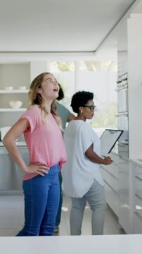 Vertical video: Entering kitchen, Diverse trio touring oven, signing paperwork and celebrating