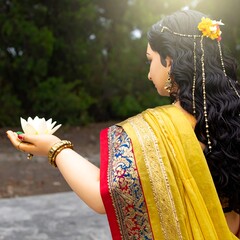 Woman in traditional attire holding lotus flower