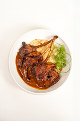 Top view of grilled lamb chops with sauce on plate