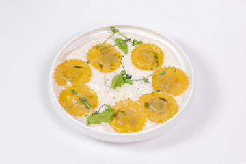 Ravioli in creamy sauce with green puree and microgreens