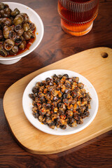 Spicy Stir-Fried Whelk Seafood Dish on Wooden Base - Traditional Asian Cuisine