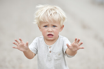frightened child reaches out with both hands in moment of despair against ultrabright solid background