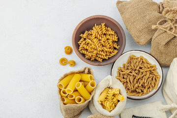 Pasta. Various kinds of uncooked pasta and noodles over light stone background. Traditional Italian
