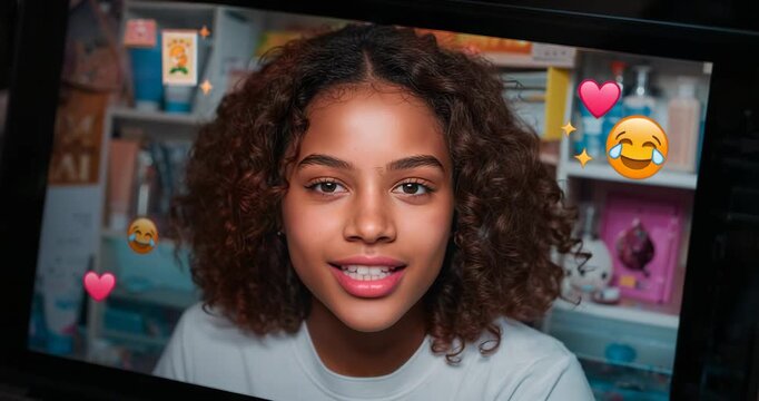Smiling teenage girl speaking into screen frame at desk, with floating emojis causing engagement