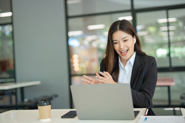 Asian businesswoman video chatting on laptop at office and modern building