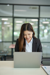 Asian businesswoman video chatting on laptop at office and modern building