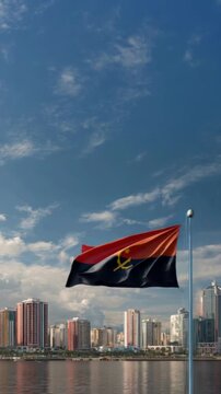 The Angolan flag flutters in the wind above the vibrant city skyline of Luanda, marking national pride and celebration.