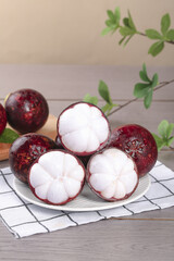 Fresh mangosteen tropical fruit halves showing white flesh segments on plate with shallow focus