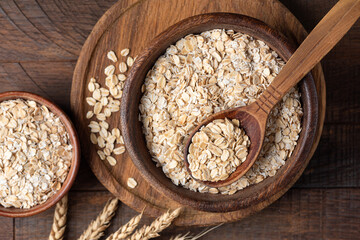 Rolled oats, oat flakes in a wooden bowl. Healthy cereals. Rustic style, top view